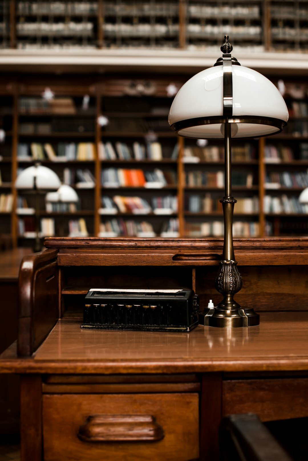 Antique wooden desk with open books and a reading lamp